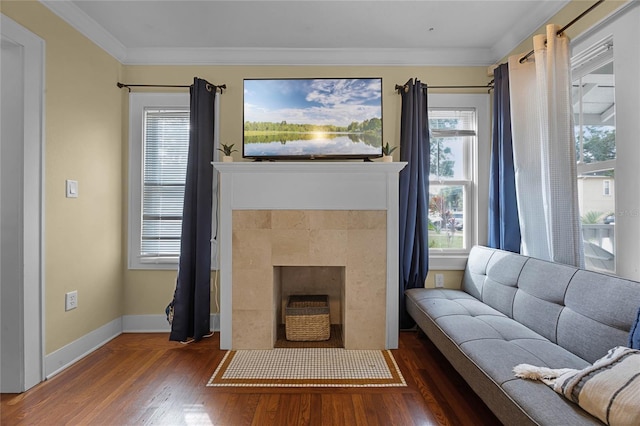 living room featuring ornamental molding, dark wood-type flooring, a tile fireplace, and baseboards