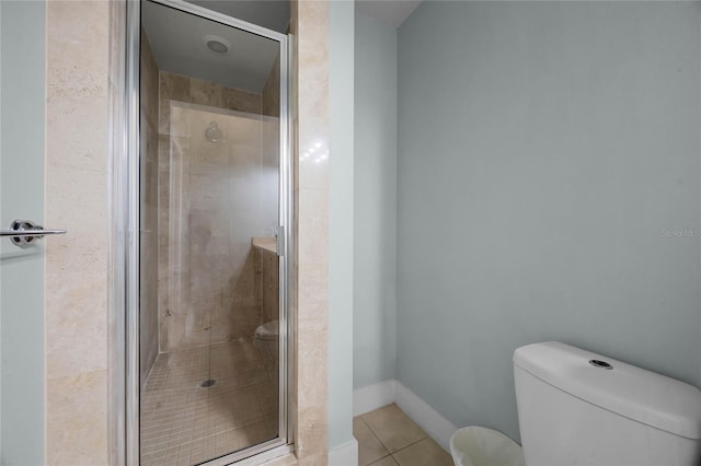 bathroom featuring baseboards, a shower stall, toilet, and tile patterned floors