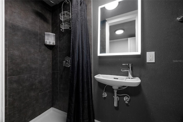 bathroom featuring a textured wall, a sink, and a shower stall