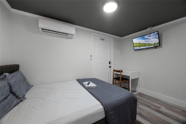 bedroom with baseboards, a wall mounted air conditioner, wood finished floors, and crown molding