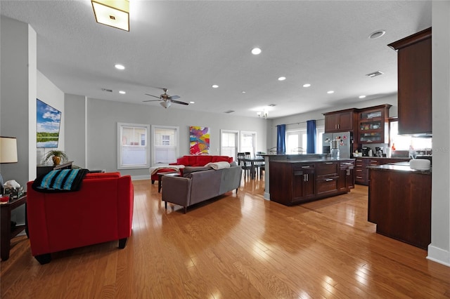 living room featuring a textured ceiling, ceiling fan, recessed lighting, visible vents, and light wood finished floors