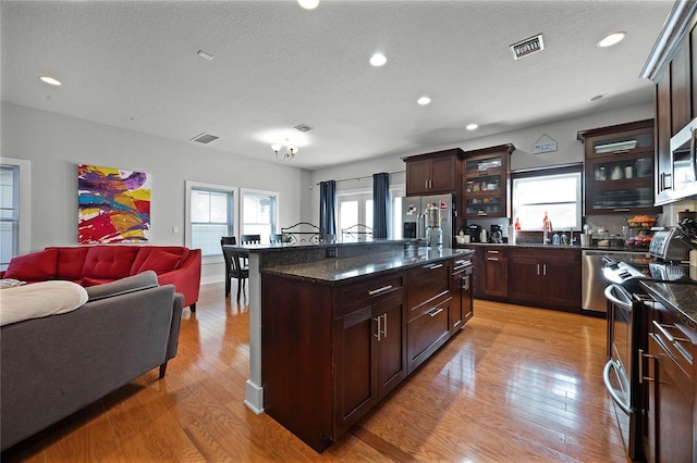 kitchen featuring visible vents, appliances with stainless steel finishes, glass insert cabinets, and a center island