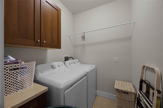 laundry area with light tile patterned floors, cabinet space, baseboards, and separate washer and dryer