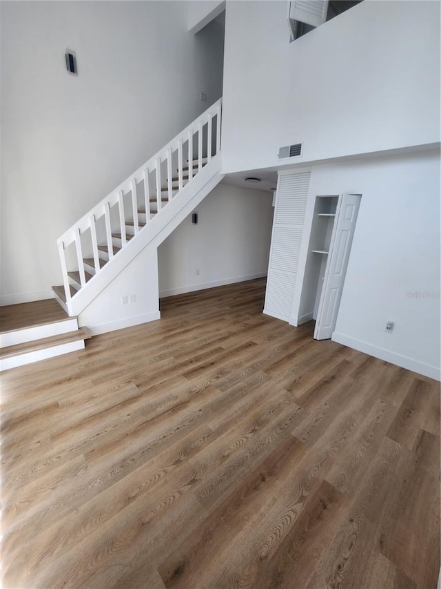 unfurnished living room featuring a high ceiling and wood-type flooring