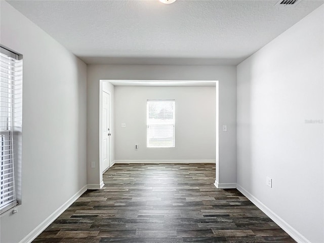 spare room featuring dark hardwood / wood-style floors and a textured ceiling