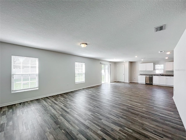 unfurnished living room with dark wood-type flooring and a textured ceiling