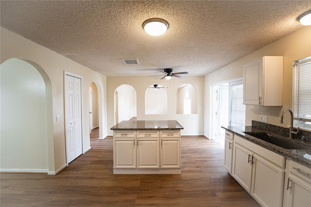 kitchen with sink, dark stone counters, and white cabinets