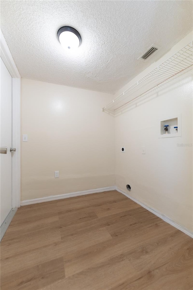 laundry area with electric dryer hookup, hookup for a washing machine, wood-type flooring, and a textured ceiling