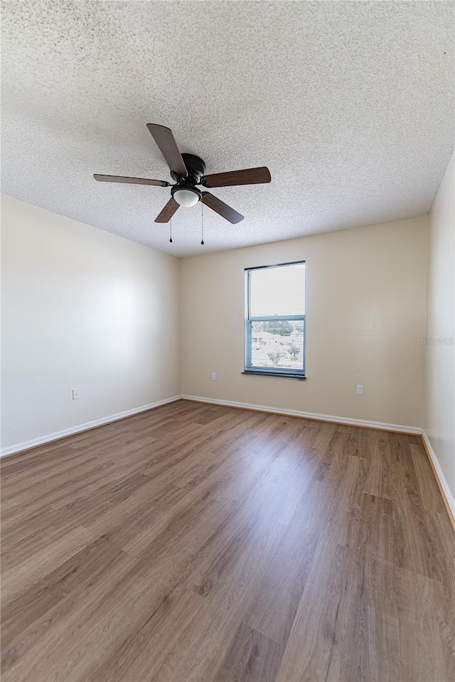 empty room featuring ceiling fan, hardwood / wood-style flooring, and a textured ceiling