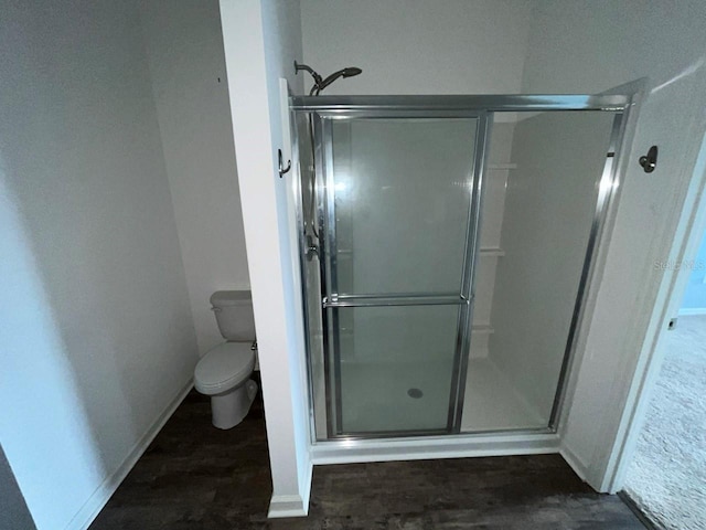 bathroom with hardwood / wood-style flooring, toilet, and walk in shower