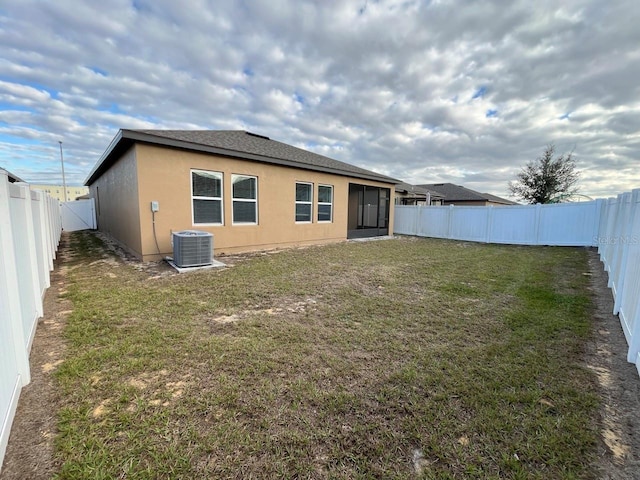 back of house with cooling unit and a lawn