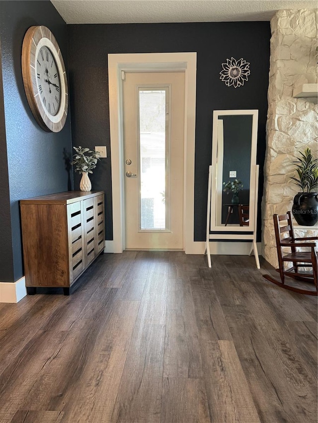 doorway with dark wood-type flooring and a textured ceiling