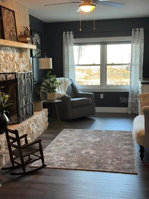 living room with dark hardwood / wood-style floors, ceiling fan, a fireplace, and a wealth of natural light