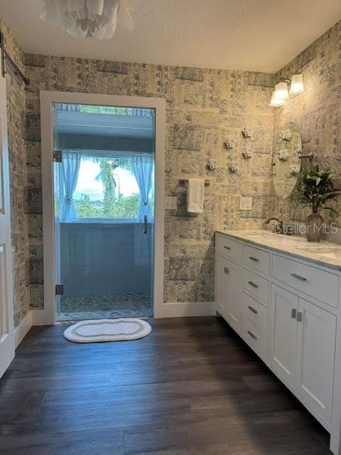 bathroom featuring vanity, wood-type flooring, a shower with door, and a textured ceiling