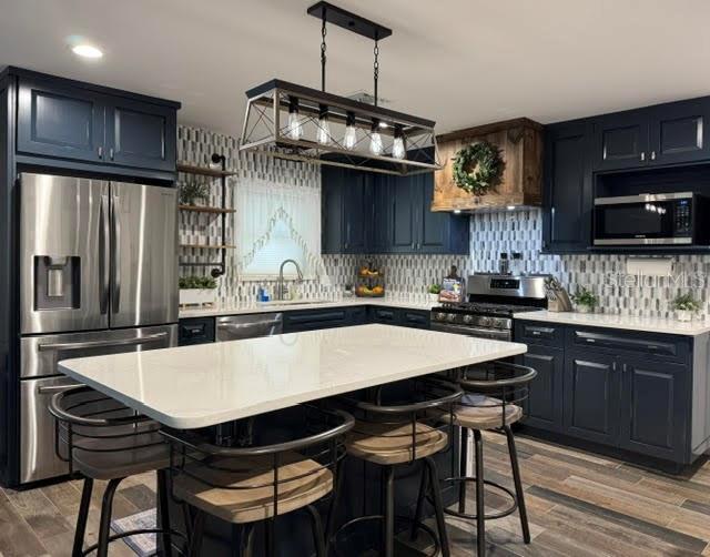 kitchen with appliances with stainless steel finishes, a breakfast bar, and a kitchen island