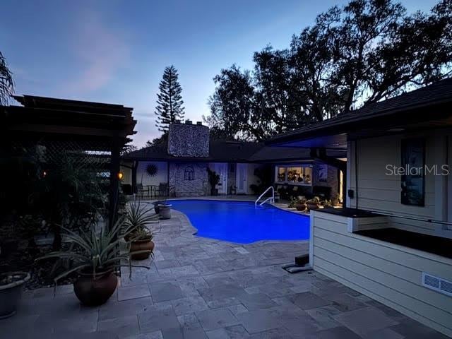 pool at dusk featuring a patio area