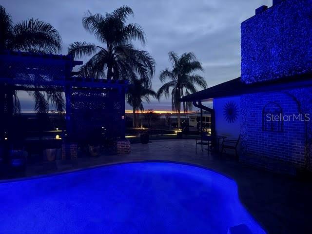 pool at dusk with a patio area