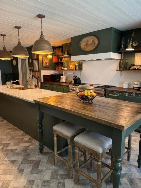 interior space featuring wood counters, sink, a kitchen breakfast bar, decorative backsplash, and hanging light fixtures