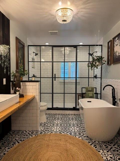 bathroom featuring toilet, separate shower and tub, tile patterned flooring, and tile walls