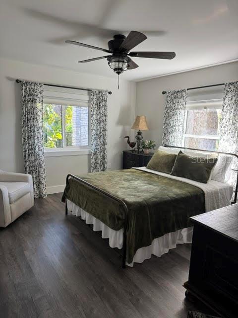 bedroom with ceiling fan, dark hardwood / wood-style flooring, and multiple windows