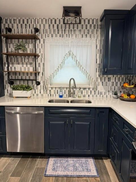 bar featuring dark hardwood / wood-style flooring, sink, decorative backsplash, and stainless steel dishwasher