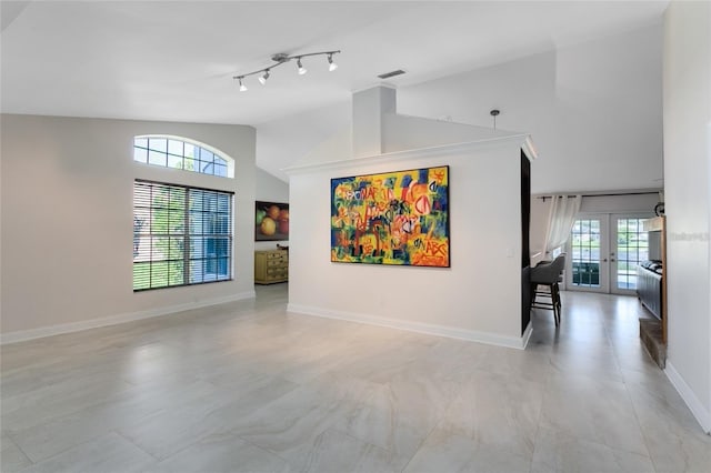 unfurnished living room with french doors, track lighting, a healthy amount of sunlight, and vaulted ceiling