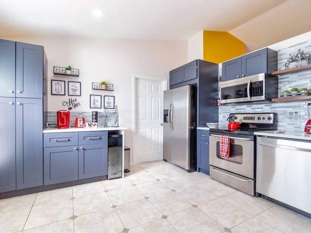 kitchen with vaulted ceiling, light tile patterned floors, appliances with stainless steel finishes, beverage cooler, and backsplash