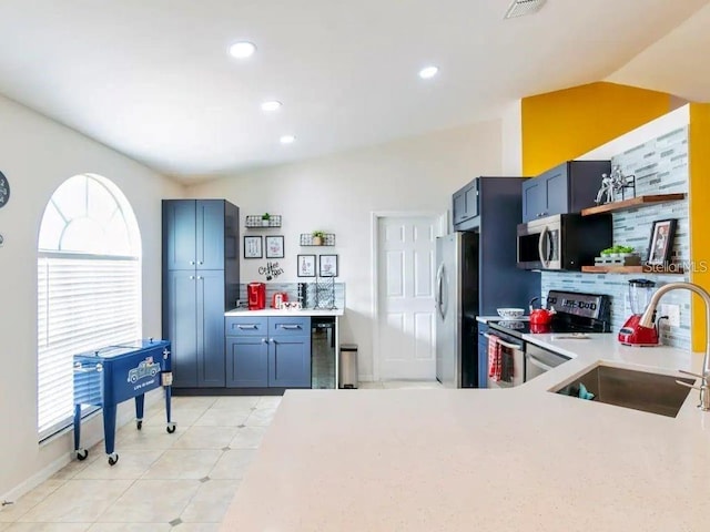 kitchen featuring sink, light tile patterned floors, backsplash, stainless steel appliances, and vaulted ceiling