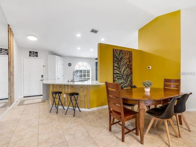 dining space featuring lofted ceiling, sink, and light tile patterned floors