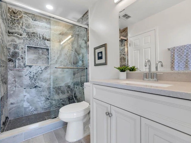 bathroom with walk in shower, vanity, toilet, and wood-type flooring