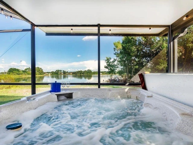 sunroom / solarium with a hot tub and a water view