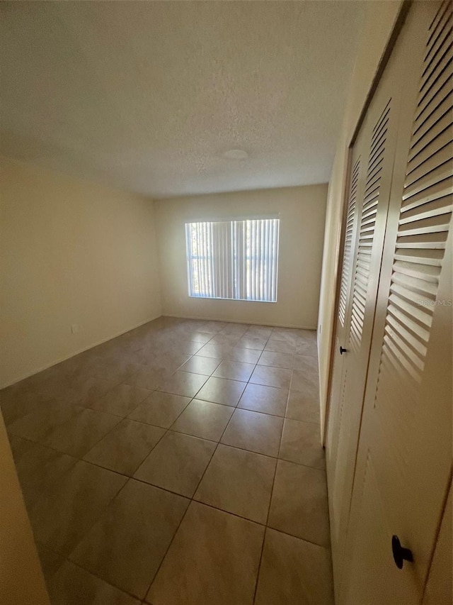 unfurnished room with a textured ceiling and light tile patterned floors