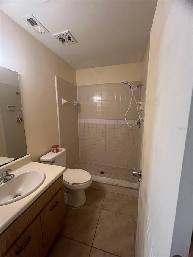 bathroom featuring tiled shower, vanity, toilet, and tile patterned flooring