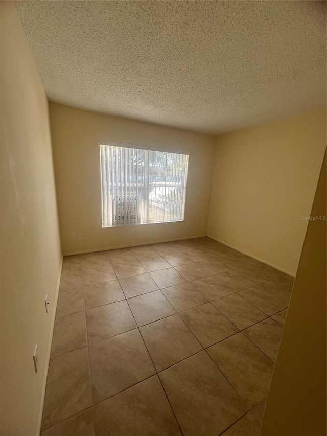 empty room with light tile patterned floors and a textured ceiling