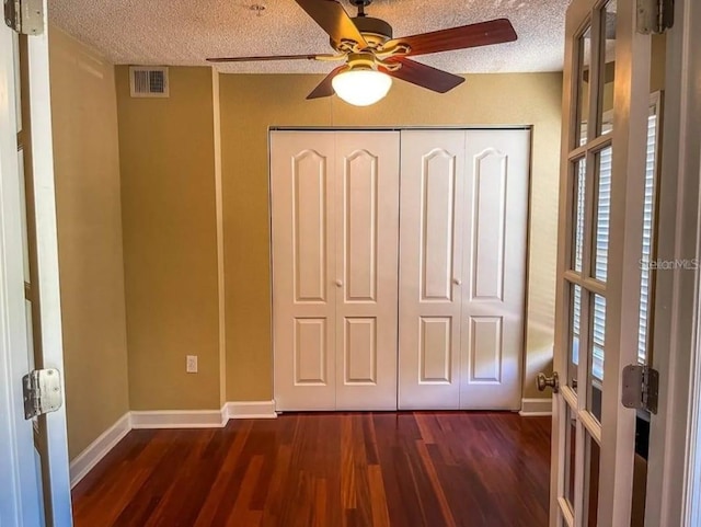 interior space featuring dark wood-type flooring, french doors, a textured ceiling, a closet, and ceiling fan