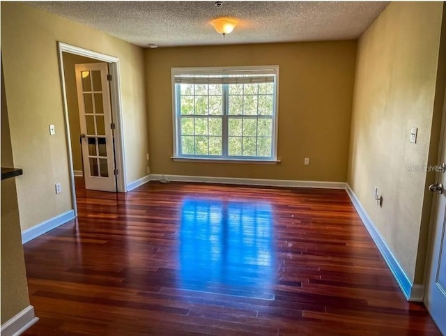 unfurnished room with dark hardwood / wood-style flooring and a textured ceiling