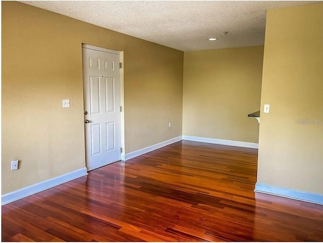 empty room with hardwood / wood-style floors and a textured ceiling