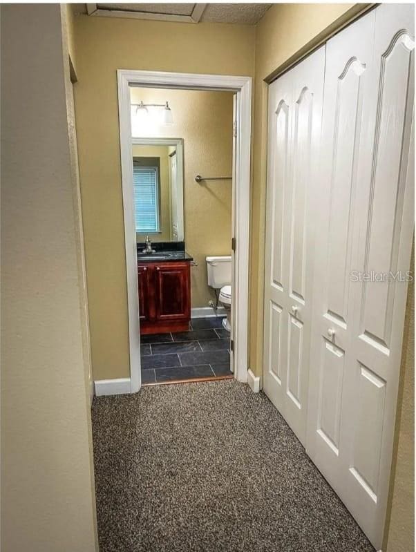 hallway featuring dark colored carpet