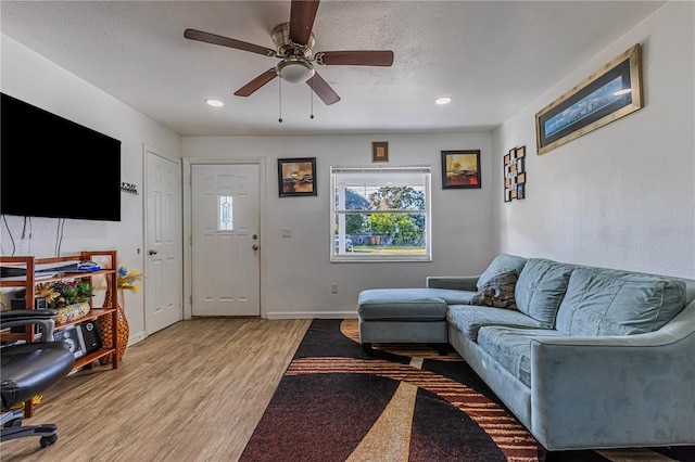 living room featuring ceiling fan, light hardwood / wood-style floors, and a textured ceiling