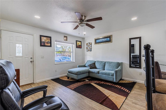 living room featuring ceiling fan, a textured ceiling, and light wood-type flooring