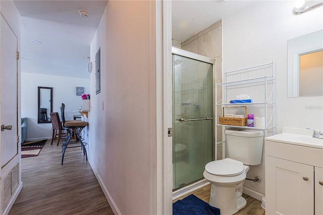 bathroom featuring vanity, hardwood / wood-style flooring, toilet, and walk in shower