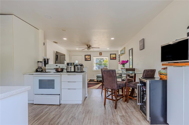 kitchen featuring ceiling fan, electric range, light hardwood / wood-style floors, and white cabinets