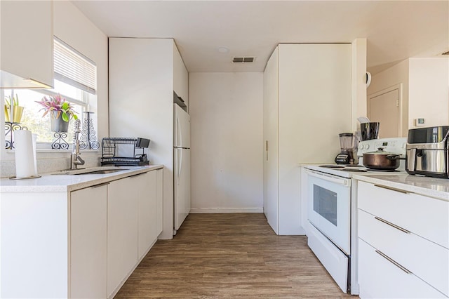 kitchen with white cabinetry, sink, white appliances, and light wood-type flooring