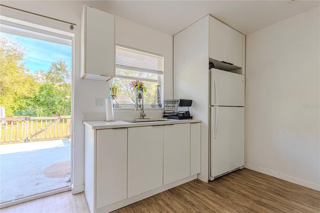 kitchen featuring light hardwood / wood-style floors, sink, white fridge, and white cabinets