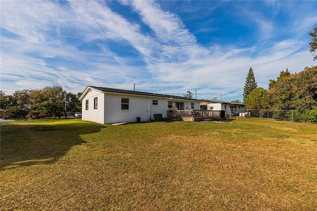 back of property with a deck and a lawn