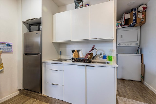 kitchen featuring stacked washer / dryer, white cabinetry, dark hardwood / wood-style floors, and stainless steel refrigerator