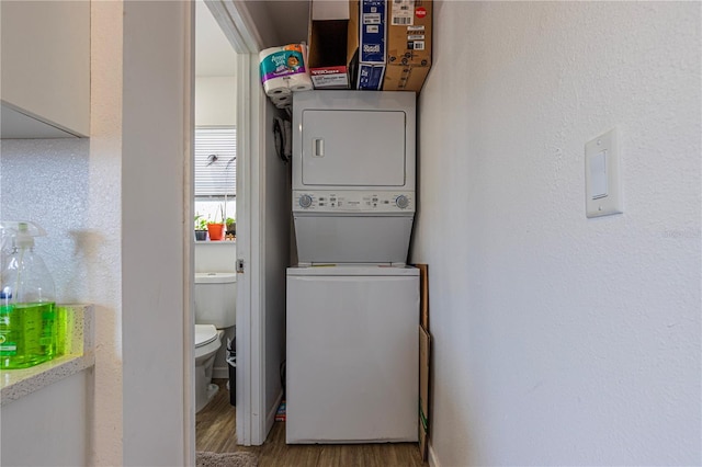 laundry room featuring stacked washer and dryer and wood-type flooring