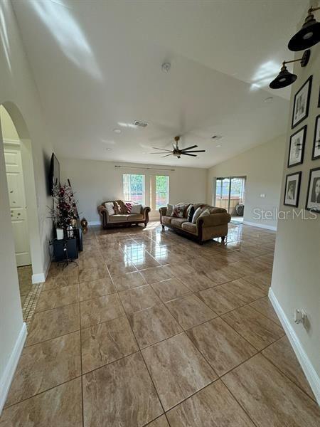 unfurnished living room featuring ceiling fan and vaulted ceiling