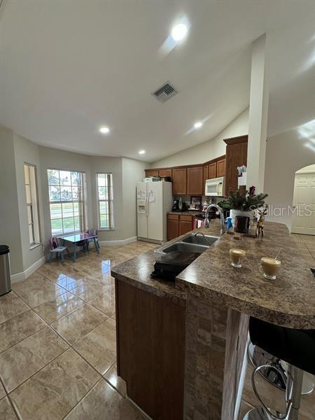 kitchen with vaulted ceiling, a breakfast bar area, white appliances, and kitchen peninsula