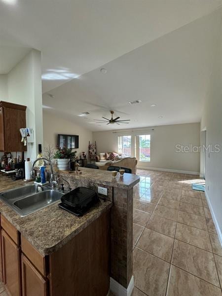 kitchen with sink, kitchen peninsula, ceiling fan, and light tile patterned flooring